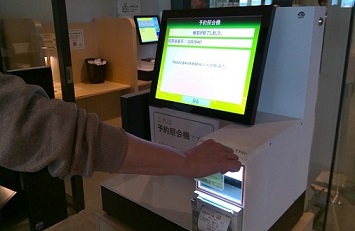 予約照会機に利用カードのバーコードをかざす写真