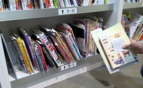 レシートと同じ番号の棚から該当の予約資料を取り出している写真